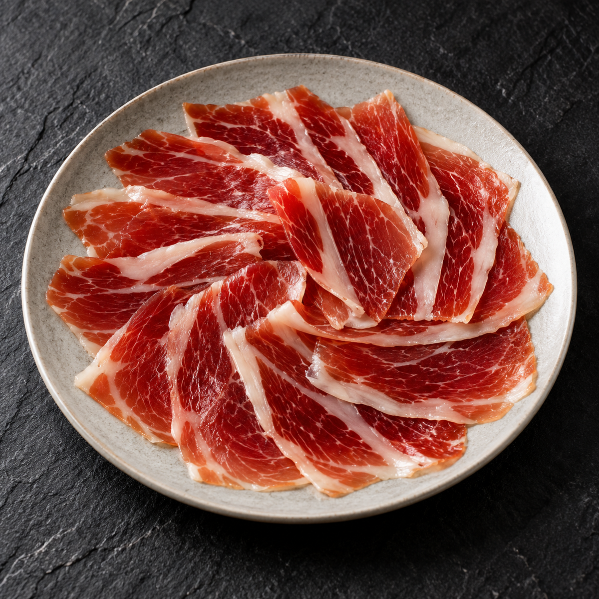 Ilustracyjna propozycja podania: łopatka Altanza Cebo de Campo 50% Ibérico, 80 g, na talerzu.