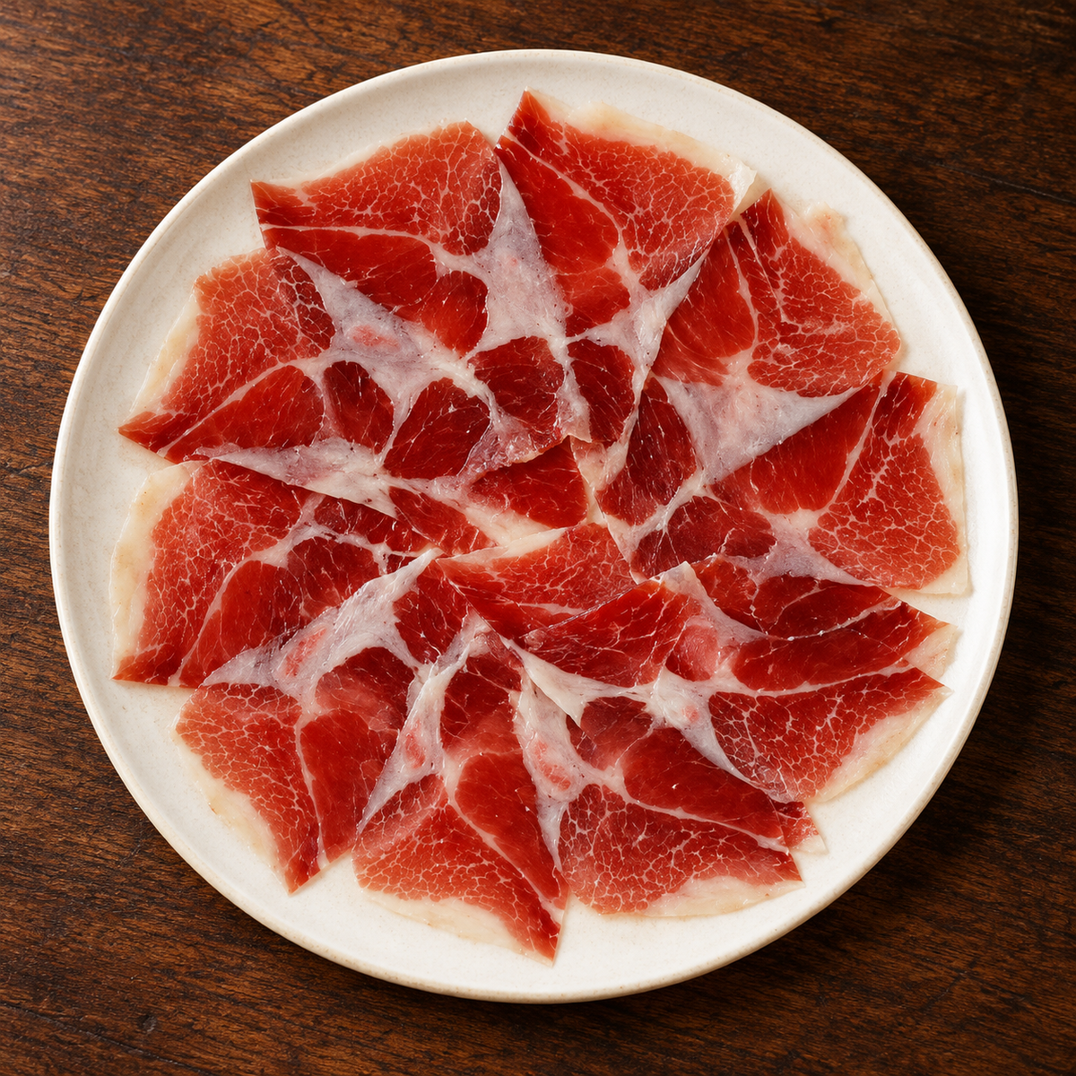 Illustrativt serveringsforslag til Altanza Cebo de Campo 50% Ibérico skinke på tallerken, 80 g, maskinskåret med knivskåret effekt.